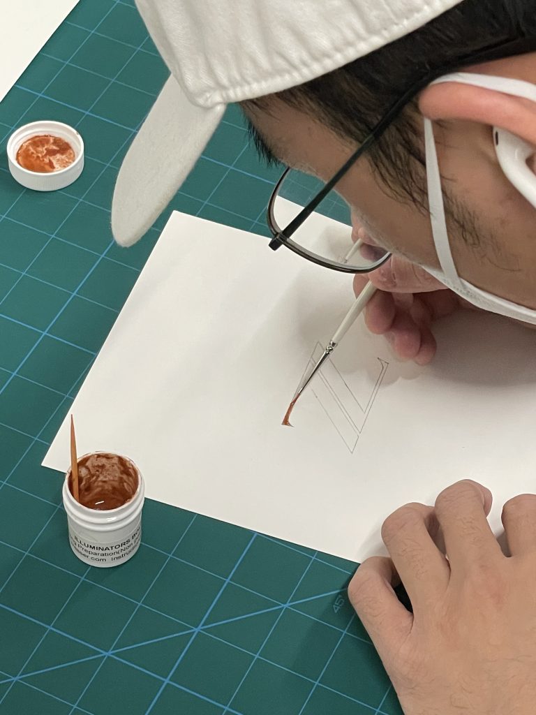 A student painting in the letter "Z" with a thin brush.